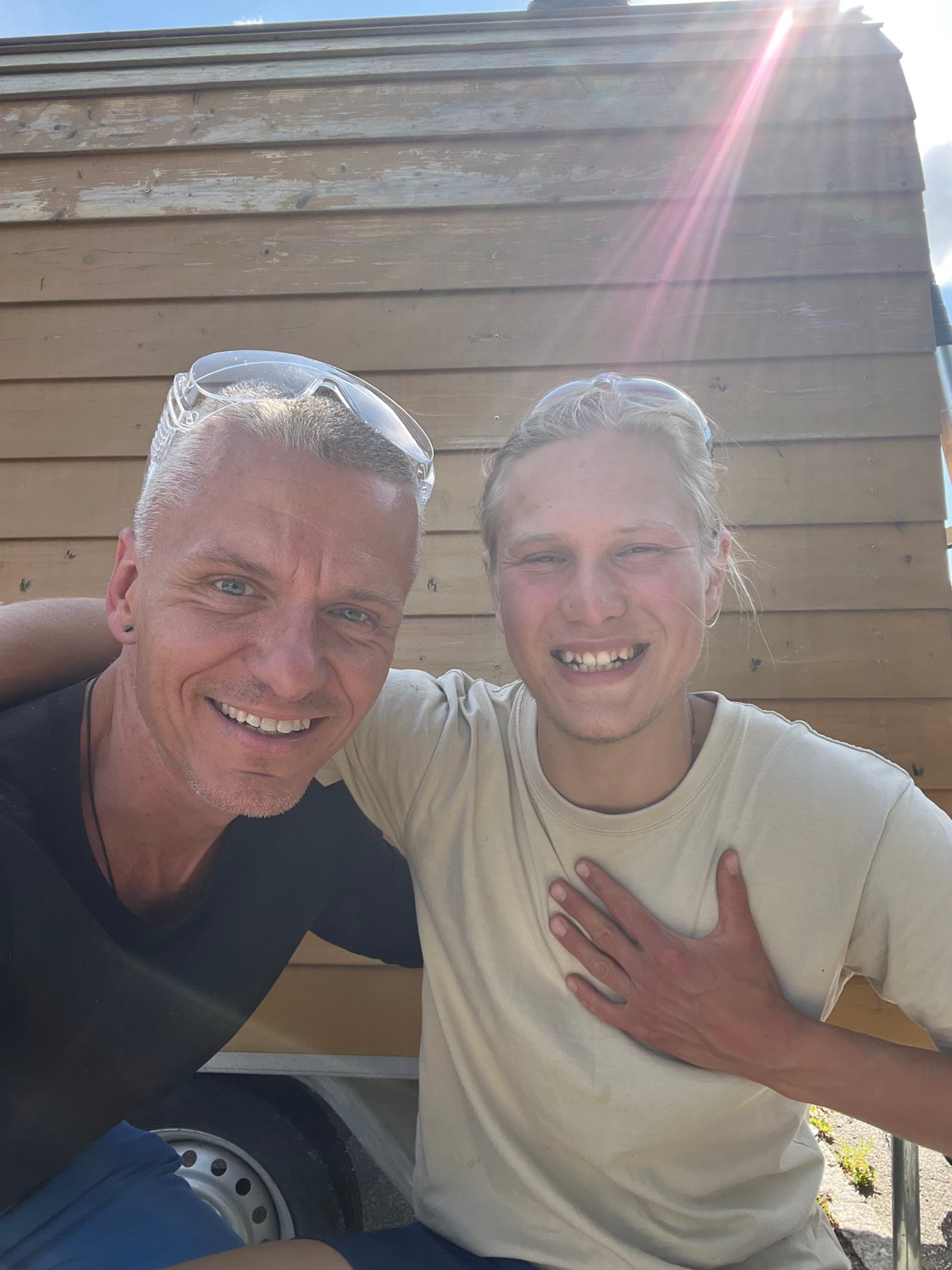 Arthur and Kay smiling in front of the wooden cabin.